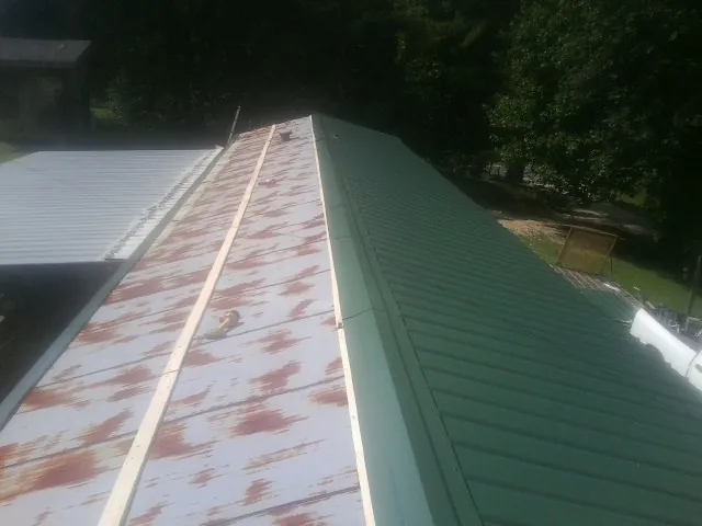 Old rusted panels beside newly installed green metal roofing — Wind Damage Roof Repair by Roofing Brothers in Albany